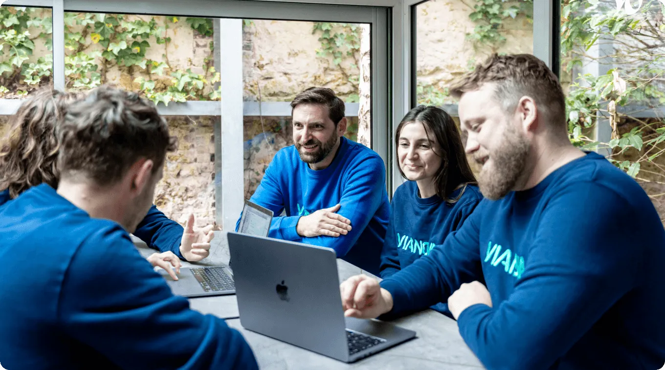 A group of people sitting around a laptop computer.